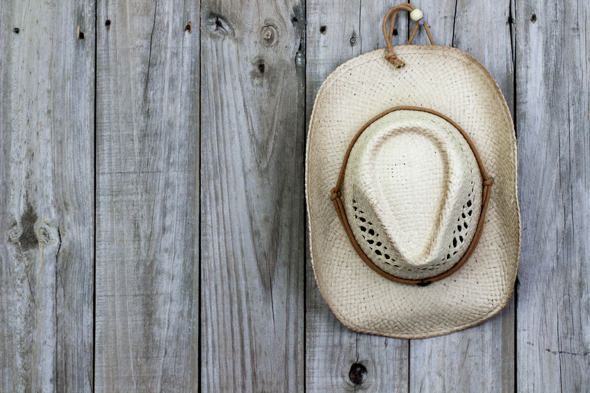 Cowboy hat hanging on rustic wood background