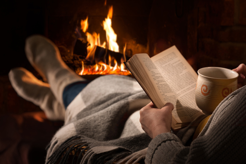 Woman resting with cup of hot drink and book near fireplace. Bild: Alexander Raths / Fotolia.com